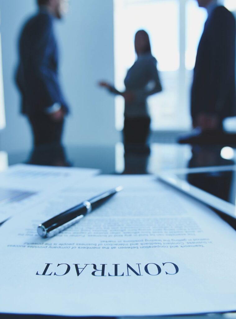 Contract on a table with people discussing in the background